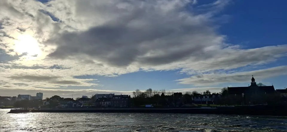Sunlit River Under Dramatic Cloudy Sky in Limerick Ireland Foto stock