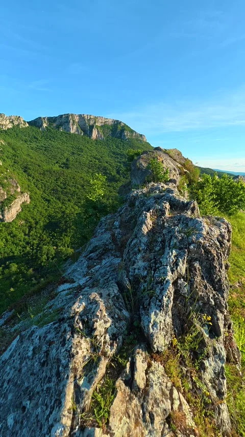 Sunlit rock ridge leads to forested peak. Sicevo Gorge, Serbia. Vertical Stock Footage 337058118