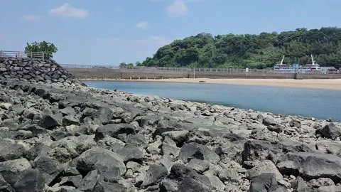 Sunlit rocks border calm ocean waters 動画素材 337696376