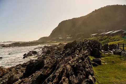 Sunlit Rocks Meet Rolling Waves. Peaceful Seaside View With Shadows And Rocky Stock Photos
