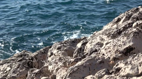 Sunlit rocky coastline with deep blue sea and natural wave sound 動画素材 342394262