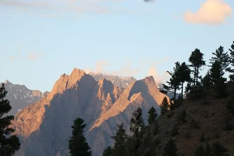 Sunlit Rocky Peaks with Pine Trees and Dramatic Skies Stock Photos