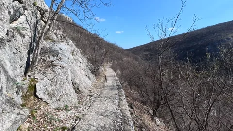 Sunlit rocky slope with sparse green growth. Balkan, Eastern Europe, POV Video stock 331454056