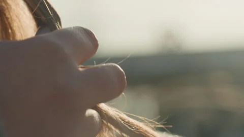 Sunlit rooftop with elegant nails. Backlit scene showing hands tucking hair into Stock Footage 342431365