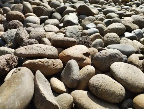Sunlit round pebble rocks, textures are evident, shadows create dimension Stock Photos