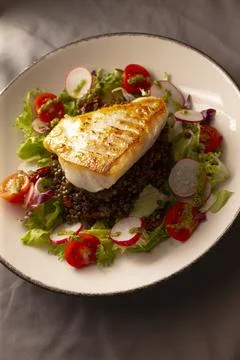 Sunlit scene featuring cooked fish and fresh garden ingredients Stock Photos