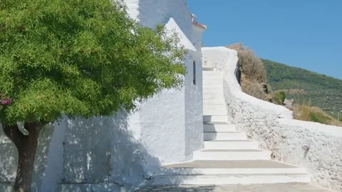 A sunlit scene featuring a traditional whitewashed church with curved walls and Stock Footage 346666269