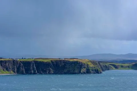 Sunlit sea cliffs and rainclouds along the coast of the Isle of Skye in Stock Photos