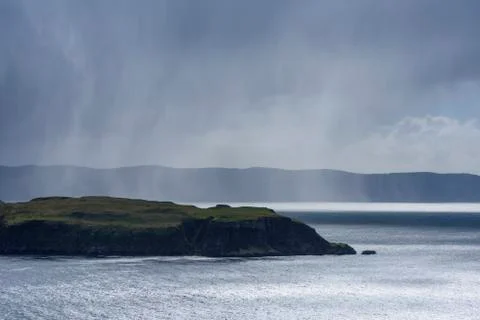 Sunlit sea cliffs and rainclouds along the coast of the Isle of Skye in Stock Photos
