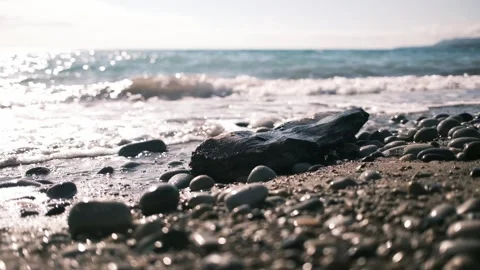 Sunlit sea waves gently breaking over a pebble shoreline. Sparkling water Stock Footage 325738535