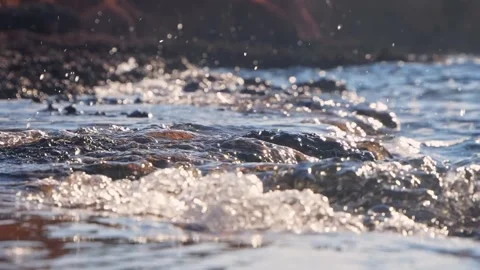 Sunlit Shallow Water Splashing Over Rocky Shoreline With Bokeh Highlights Stock Footage 337419667