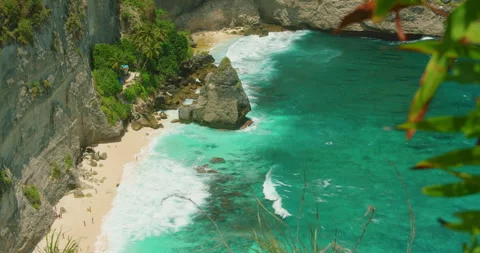 Sunlit shoreline of Diamond Beach seen through green leaves at Nusa Penida Stock Footage 344772908