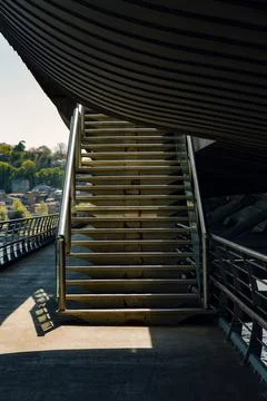 A sunlit stairway to  upper deck of a bridge. Stock Photos