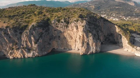 Sunlit steep rocks over turquoise sea. Aerial shot of cliffy coastline. Palinuro Stock Footage 99002392