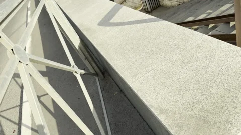 Sunlit stone ledge and metal fence border an urban stairway descent Stock Footage 336937556