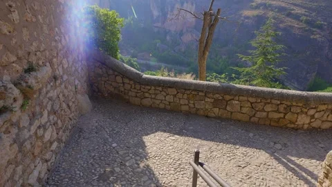 Sunlit stone wall overlooking cliffs and trees in the Huecar valley beside San Stock Footage 340883014