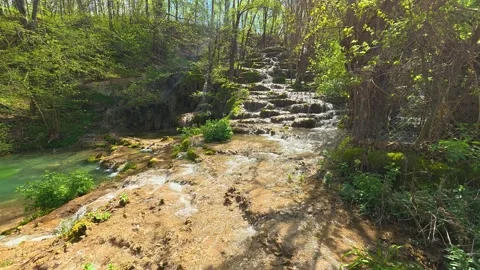 Sunlit stream cascades over mossy stones. Balkan, Eastern Europe, POV Video stock 333589371
