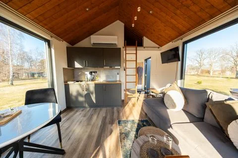 Sunlit tiny house interior with pitched wood ceiling and kitchenette Foto stock