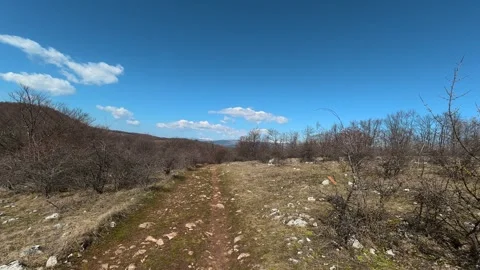 Sunlit trail winds through dry, rocky terrain. Balkan, Eastern Europe, POV Video stock 331778541