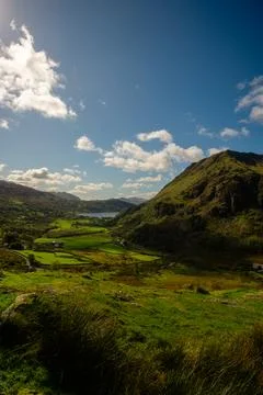 Sunlit valley with green fields and Llyn Gwynant lake, Snowdonia, Wales Stock Photos