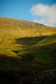 Sunlit valley slopes with mountain shadow and stream in Snowdonia, Wales Stock Photos