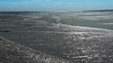 Sunlit waves roll toward dark sands Stock Footage 346260151