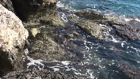 Sunlit waves splashing over rugged limestone coastal rocks Video stock 342394233
