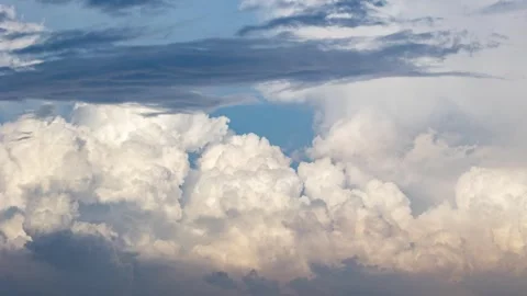 Sunlit white cumulus clouds drifting slowly across a clear blue sky Stock Footage 342328373