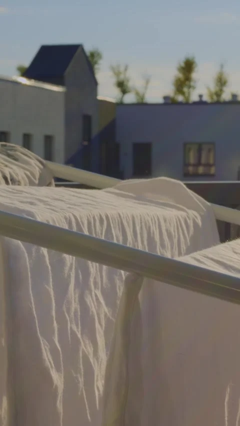 Sunlit white sheets drying on balcony, sunlight highlighting fabric ripples and Video stock 344717692