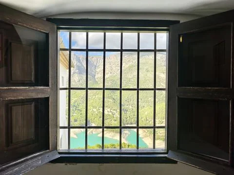 Sunlit window overlooking tranquil pool, bright opening showing serene mountain Stock Photos