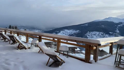 Sunloungers covered in snow on a deck with a mountain view Stock Footage 170784483