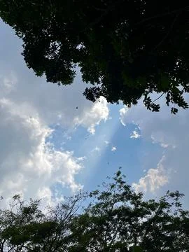 Sunnbeams breaking through white clouds in blue sky framed Stock Photos
