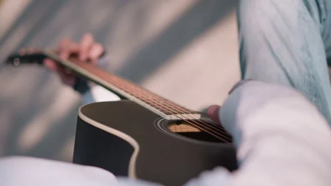 Sunny acoustic performance tutorial. Strumming lead on sunny park bench scene Stock Footage 331258616