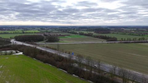 Sunny and cloudy winter day in german rural town. Farm fields with driving cars Stock Footage 299604611