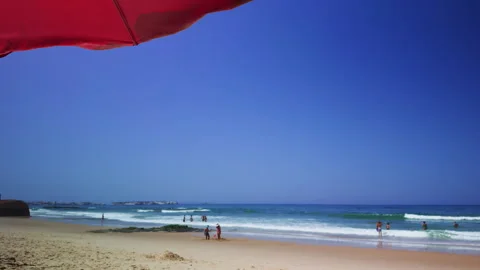 Sunny Beach Day with Surfers View from Under Umbrella Stock Footage 344947770
