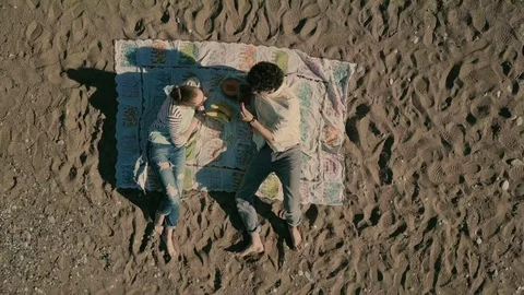 On a sunny beach, a loving couple eats fruit. Stock Footage 78649235