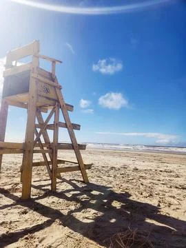 A sunny beach with a worn and empty lifeguard lookout chair Stock Photos