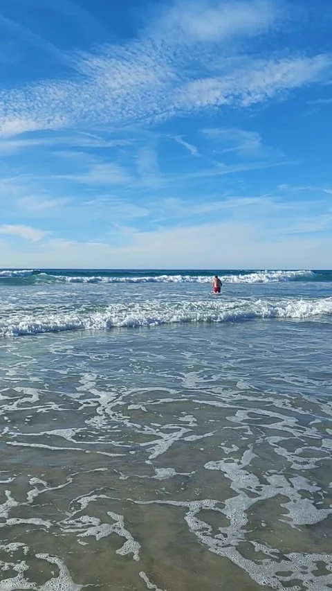 Sunny day at the beach with gentle waves and a person swimming in the Cantab Video stock 337803466