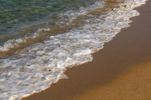A sunny day on the beach, with waves lapping the shore. Foto stock