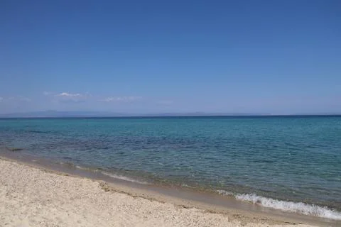 A sunny day on the beach, with waves lapping the shore Stockfoto's