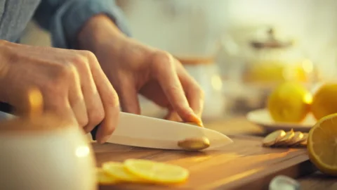 On sunny day mans hands slice fresh ginger cutting board amidst lemons utens Stock Footage 331366020
