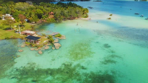 Sunny day view of Bacalar lagoon waterfront with boats and beach in Mexico Video stock 321352753