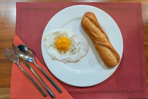 Sunny egg and bread on white plate at restaurant Foto stock