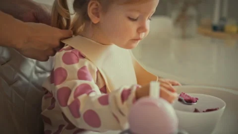 In a sunny kitchen a young mother gently slides a silicone bib apron over he Stock Footage 332481279
