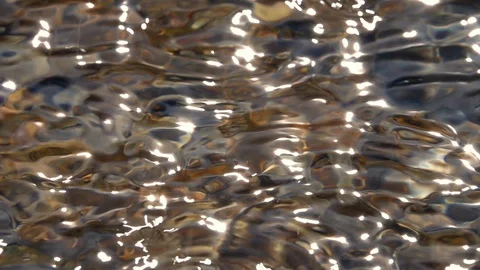 Sunny light rain with round waves in shallow pure water pebble bottom close up Stock Footage 98095339