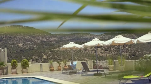 Sunny poolside area with lounge chairs and umbrellas, holiday vibe, Greece Stock Footage 328658720