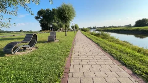 Sunny Riverside Promenade with Walking Path Along Waterfront, Slow Camera Moveme Stock Footage 339724087