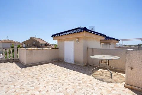 Sunny rooftop terrace with patterned tiles, small storage room and round me.. Stock Photos