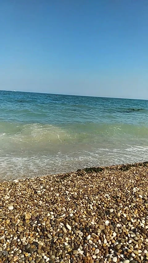 Sunny seaside view with gentle waves rolling onto a pebble beach. Stock Footage 301688174