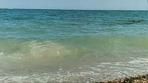 Sunny seaside view with gentle waves rolling onto a pebble beach. Stock Footage 301688184